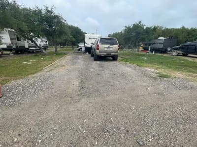 Gravel site road with RVs parked under oak trees at New Season RV Resort, Aransas Pass TX